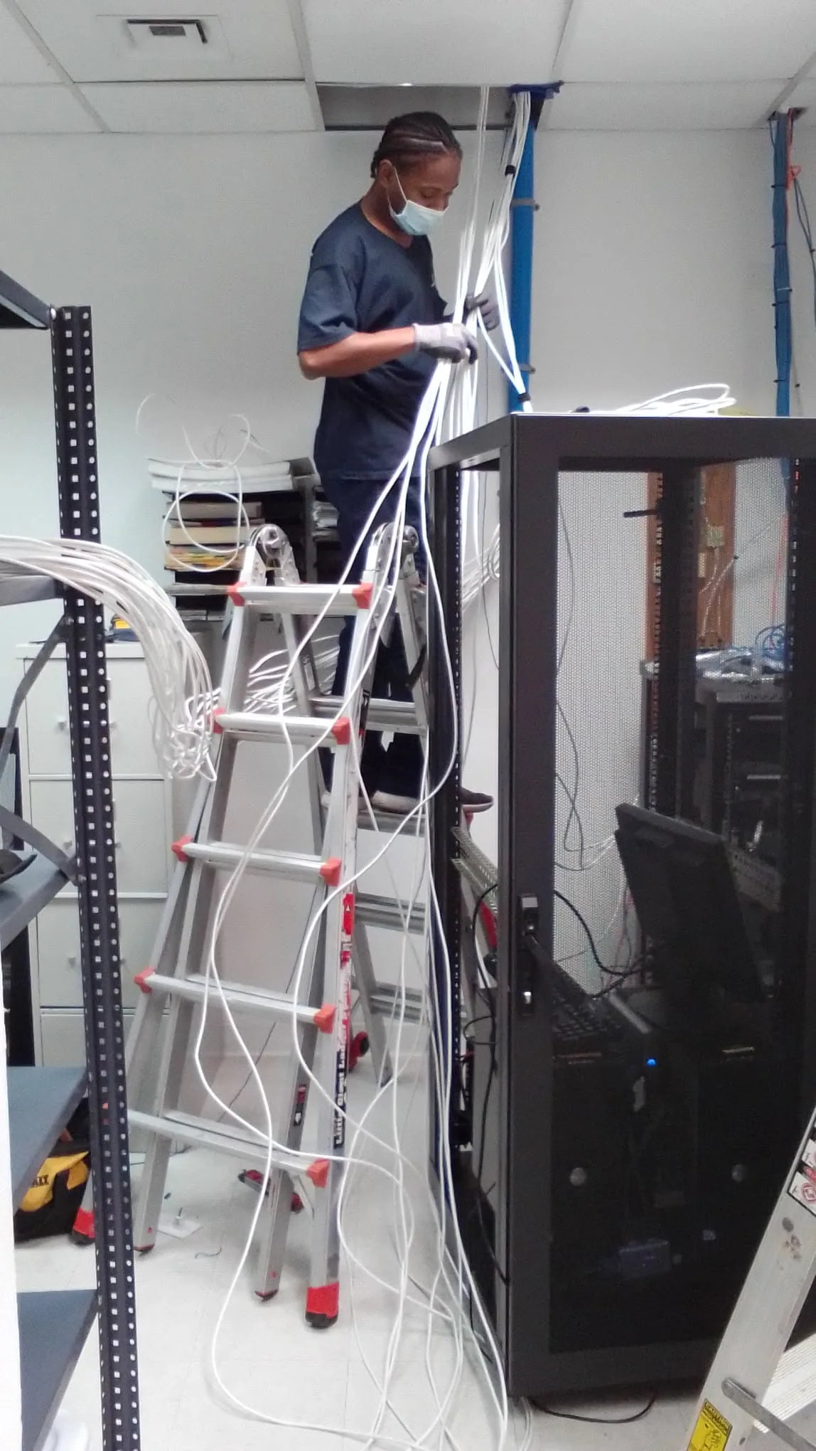 Technician routing structured cabling beside an equipment rack