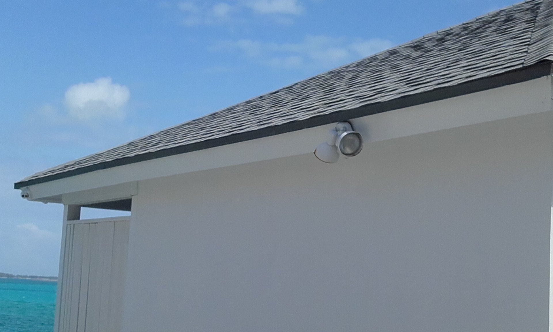 Security camera installed beneath the roofline of a coastal property