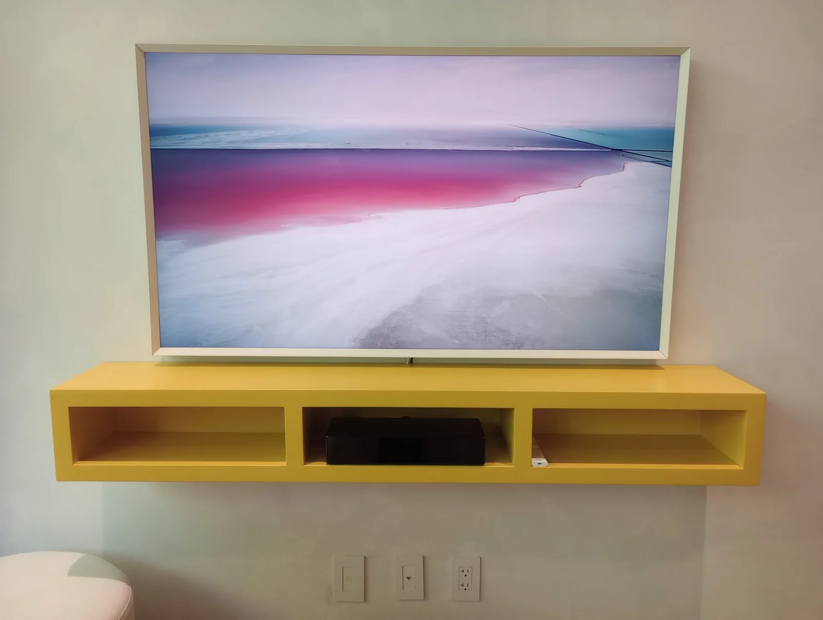 Wall-mounted television above a custom floating console with concealed equipment