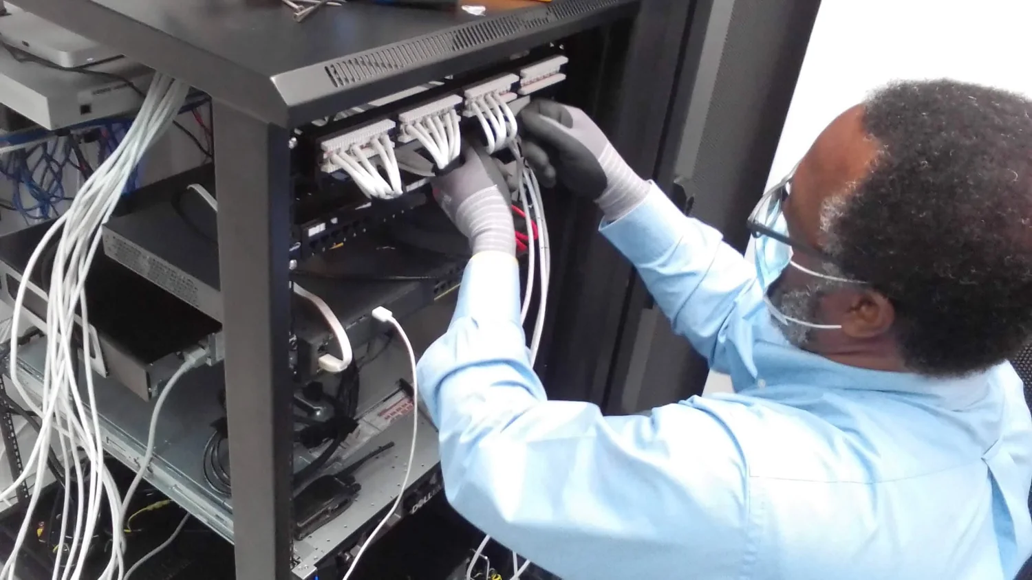 Technician terminating structured cabling inside an equipment rack