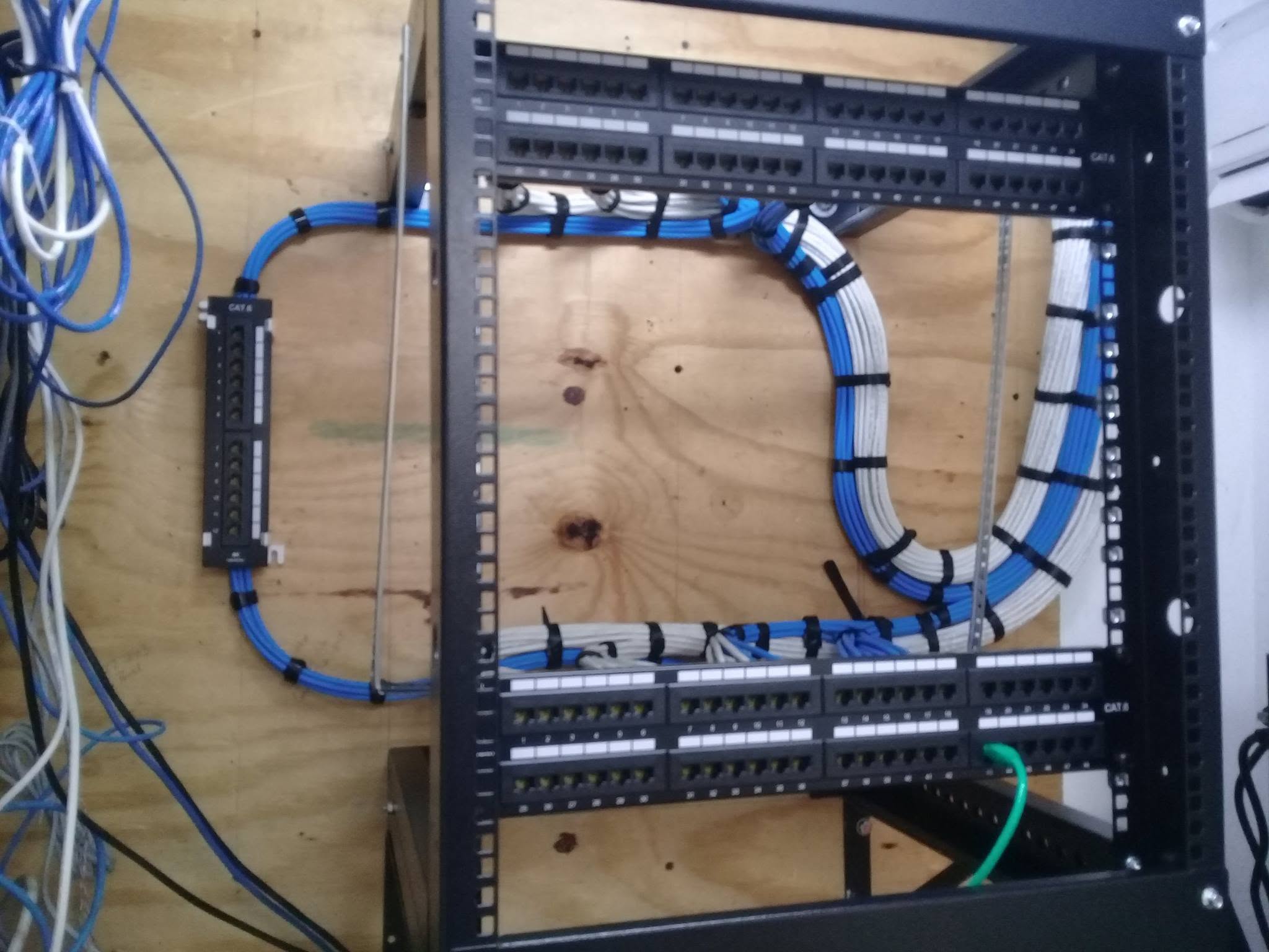 Blue and white structured cabling routed into patch panels inside a network rack