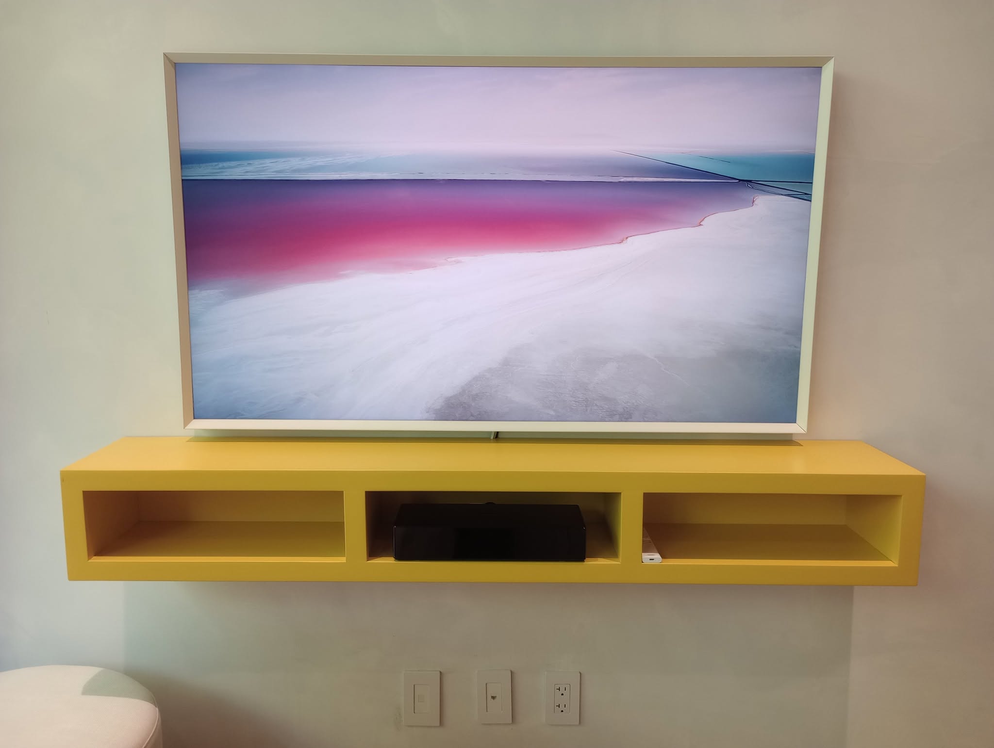 Wall-mounted television above a custom floating console